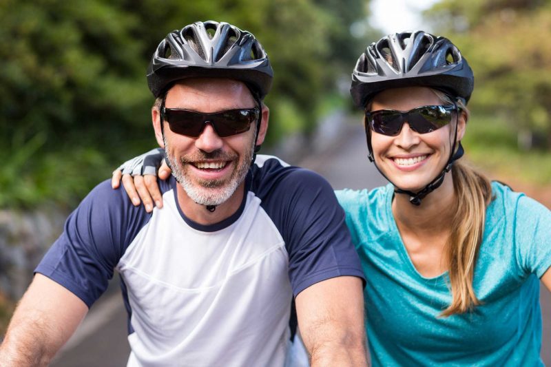 Ein Mann und eine Frau mit Helm und Sonnenbrille auf einer E-Bike Moutainbiketour mit Robinwoods Naturerlebnisse. Beide lächeln glücklich in die Kamera.